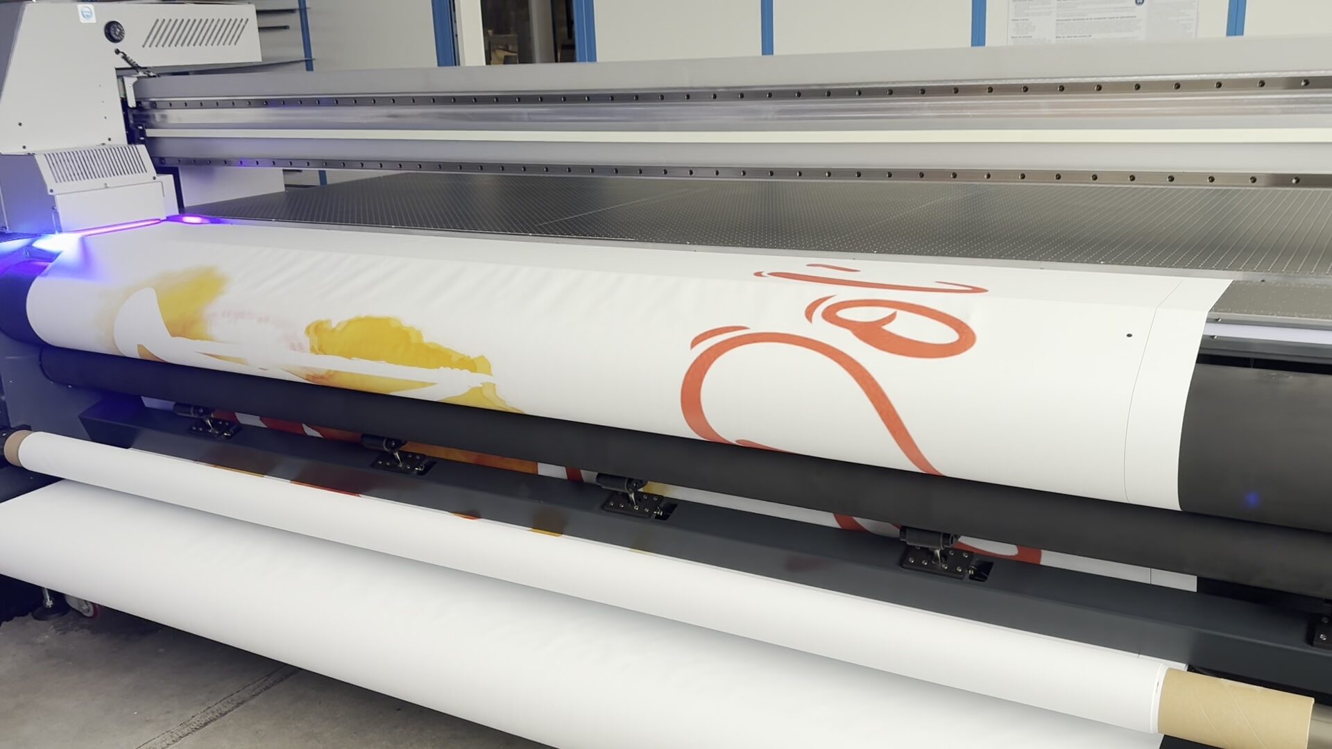 Imprimante grand format en production sur un support en rouleau dans l’atelier CMPRO